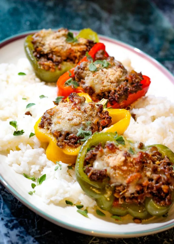 Colorful stuffed bell peppers filled with beef and lentils on a white plate
