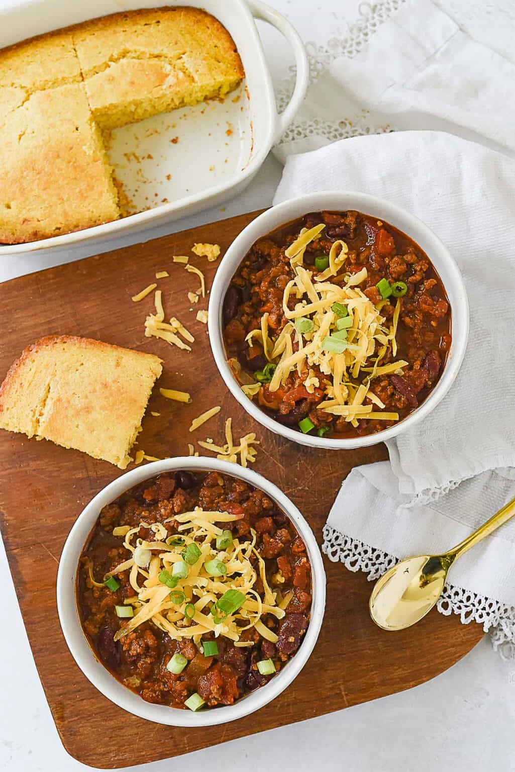 Two bowls of hearty beef chili topped with shredded cheese and sour cream