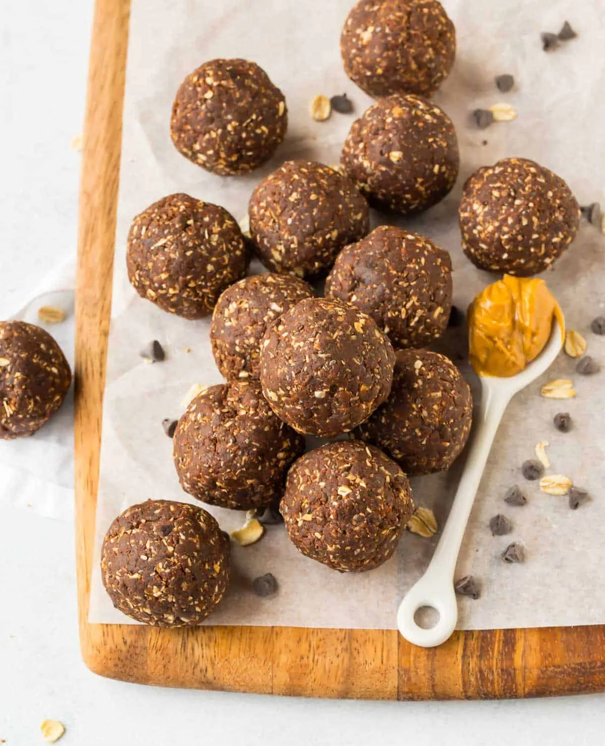 Chocolate protein balls stacked on a white plate dusted with cocoa powder