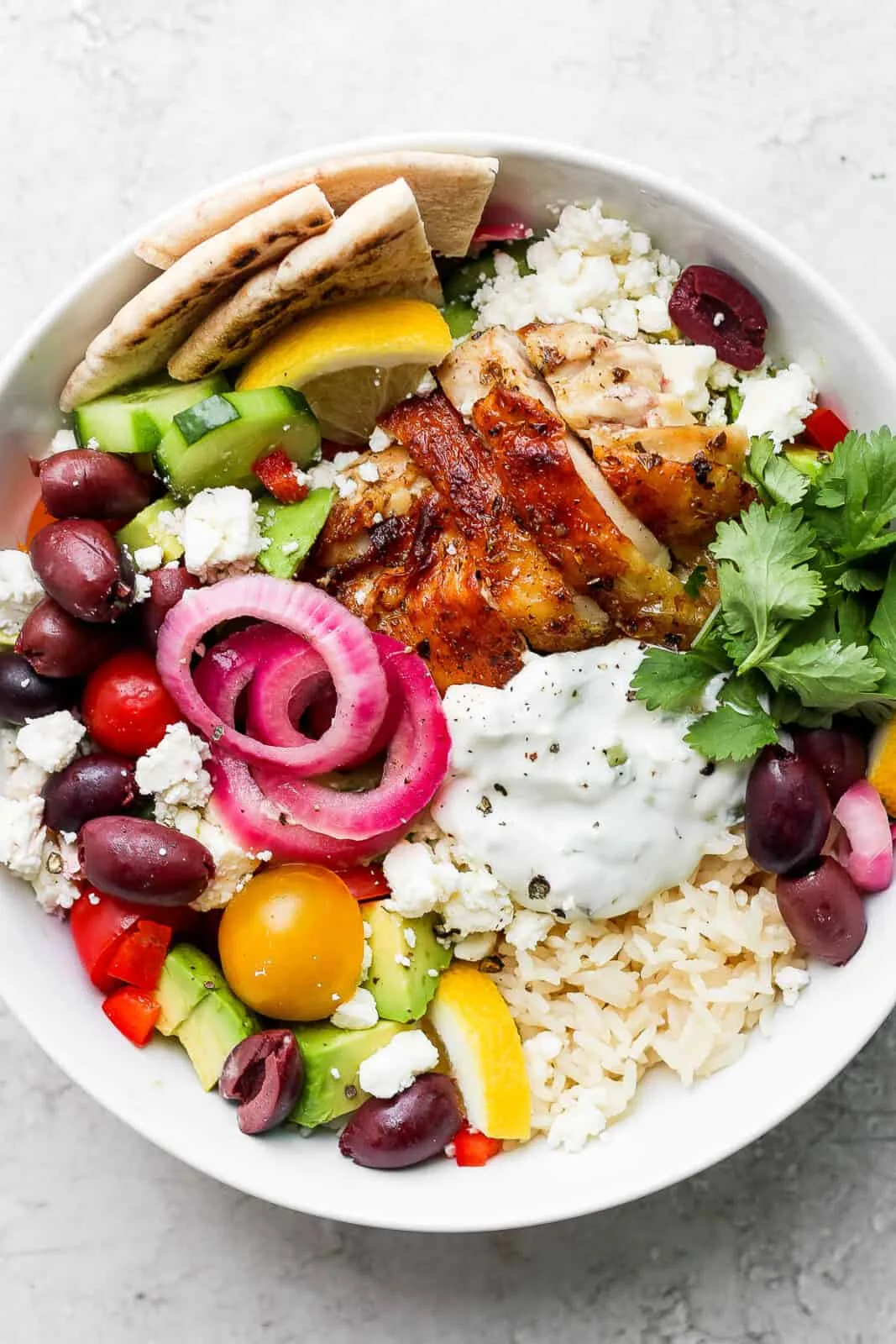Grilled chicken slices over fluffy rice with cucumber, tomatoes, and tzatziki