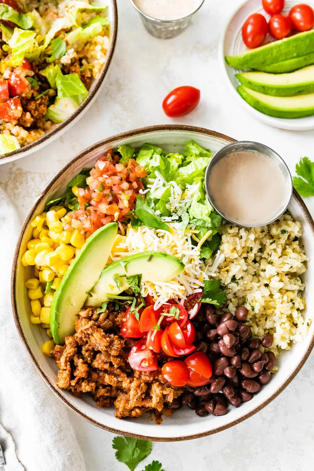 A colorful taco bowl with ground turkey, rice, black beans, and fresh toppings