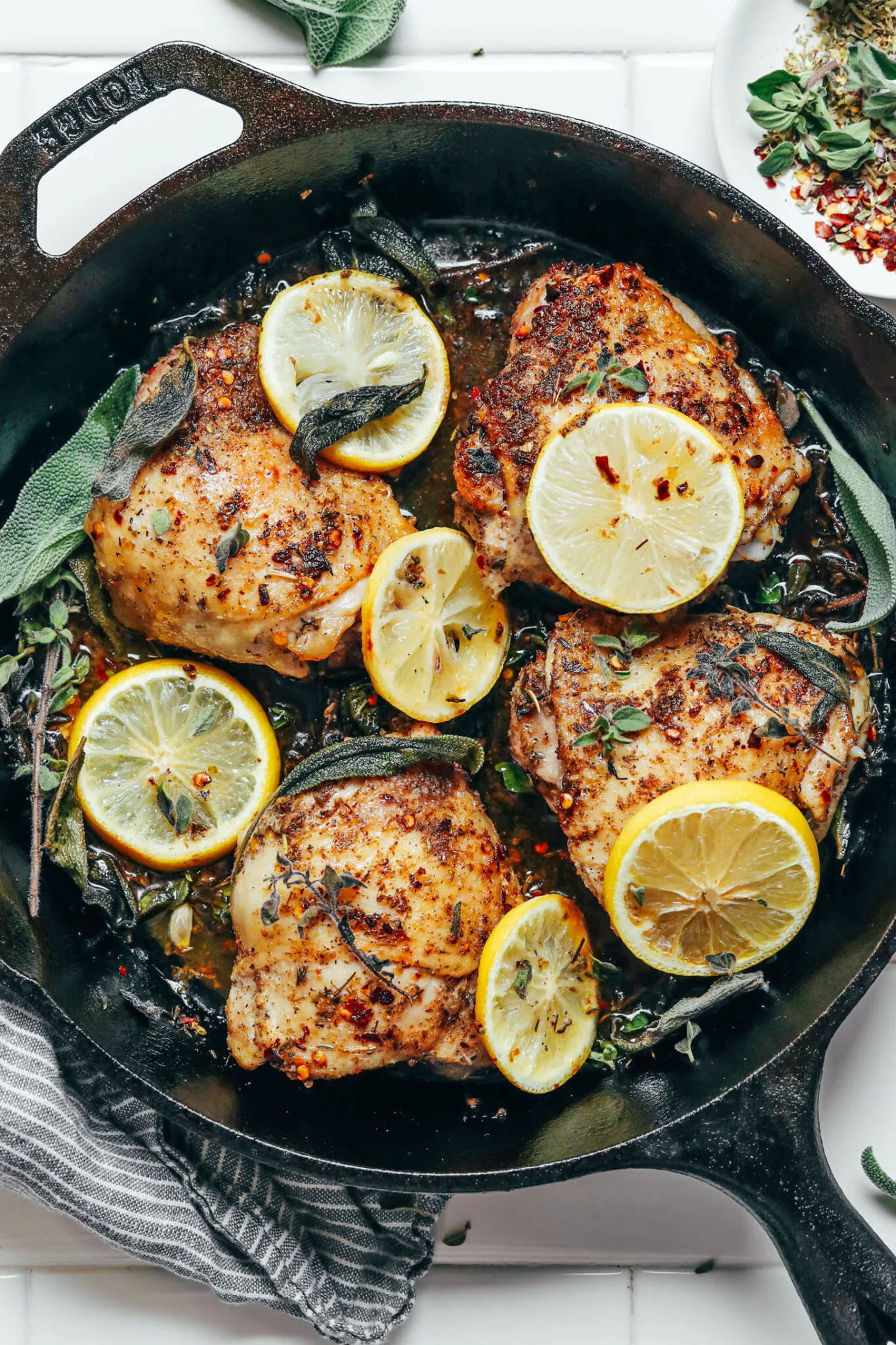Golden baked chicken thighs garnished with fresh herbs and lemon slices