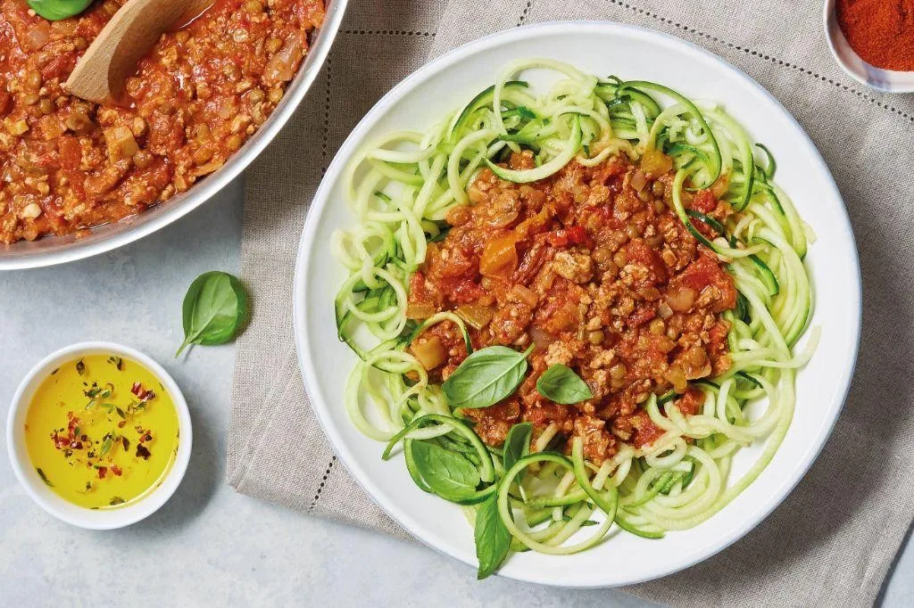 Hearty lentil and ground turkey bolognese sauce served over pasta with fresh herbs