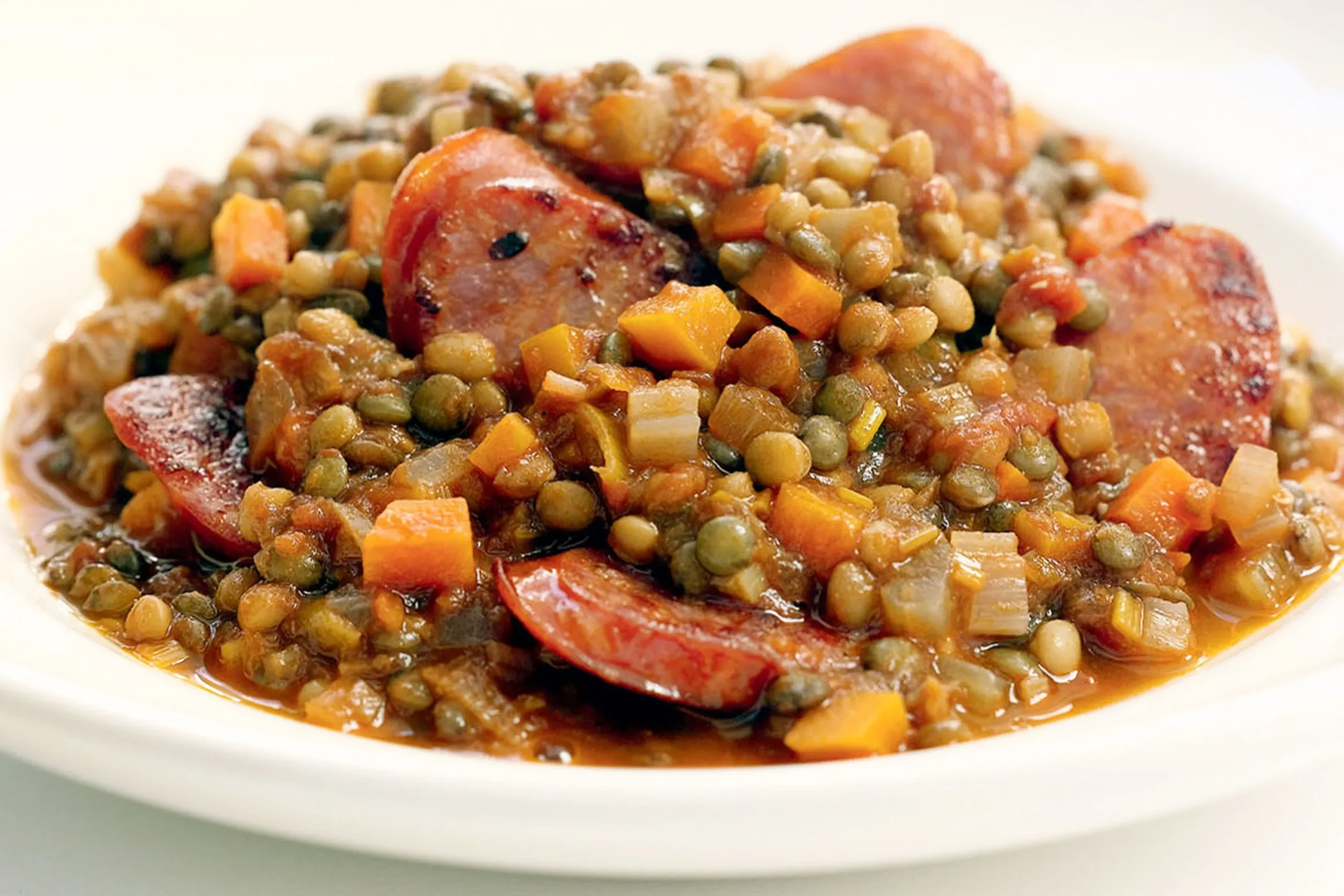Hearty lentil and sausage stew in a rustic bowl with fresh herbs