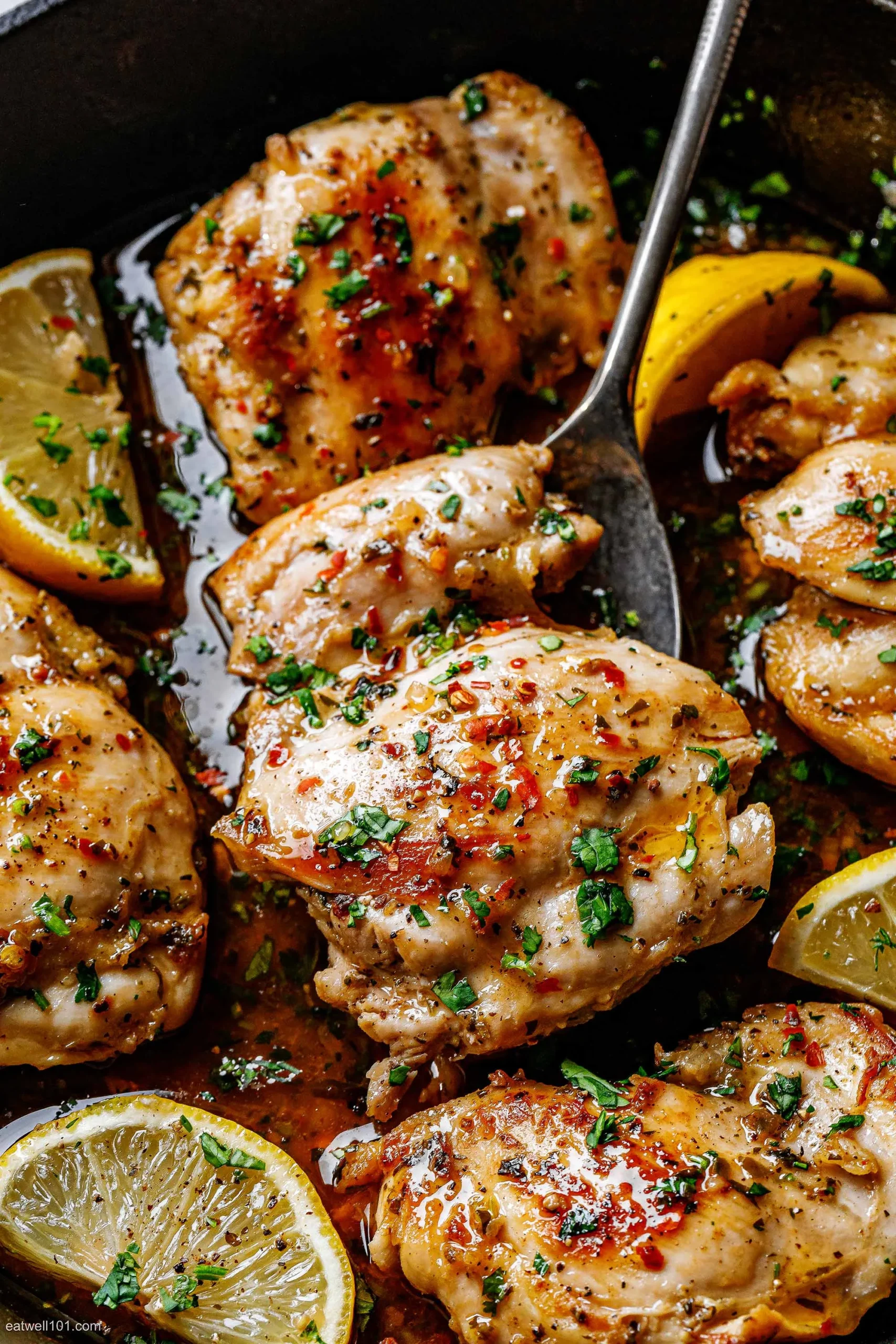 Golden baked chicken thighs with lemon slices and garlic on a sheet pan
