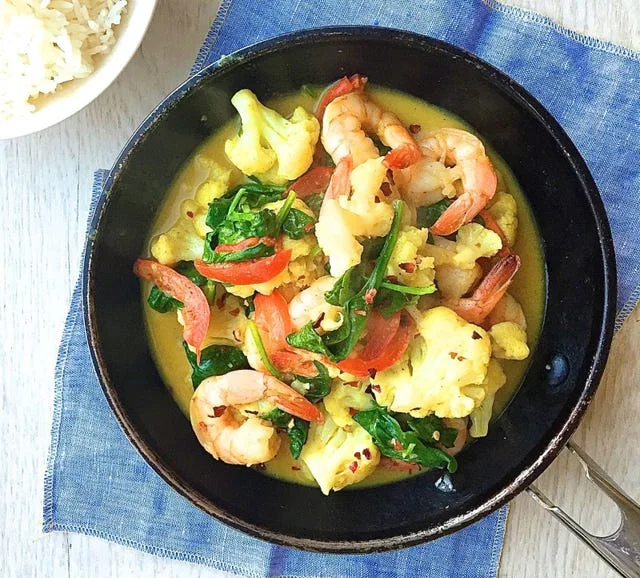 Creamy shrimp and cauliflower curry served in a bowl with fresh herbs