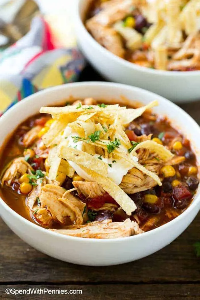 A bowl of hearty chicken enchilada soup topped with cheese and tortilla strips