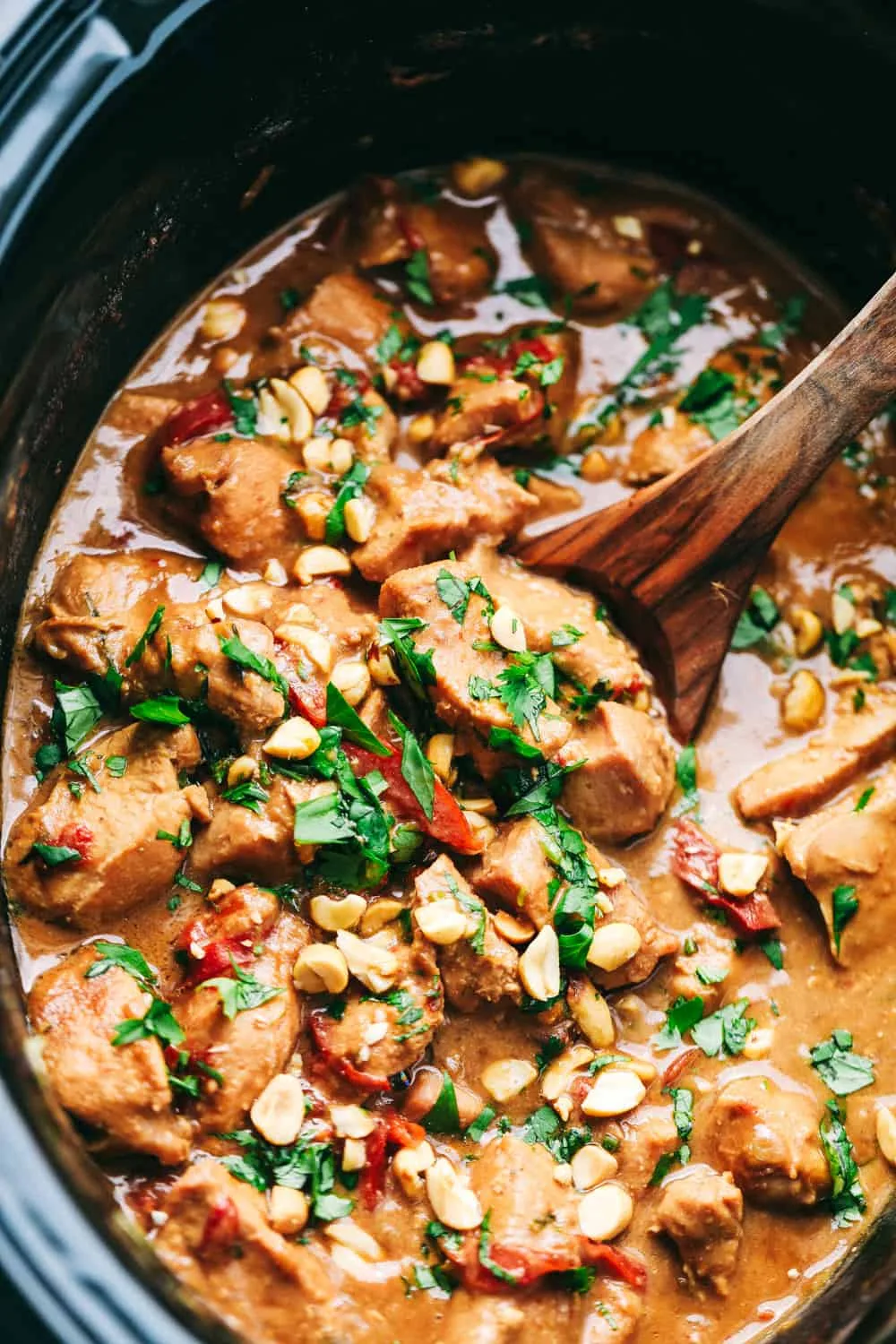 Tender chicken pieces coated in creamy peanut butter sauce in a slow cooker