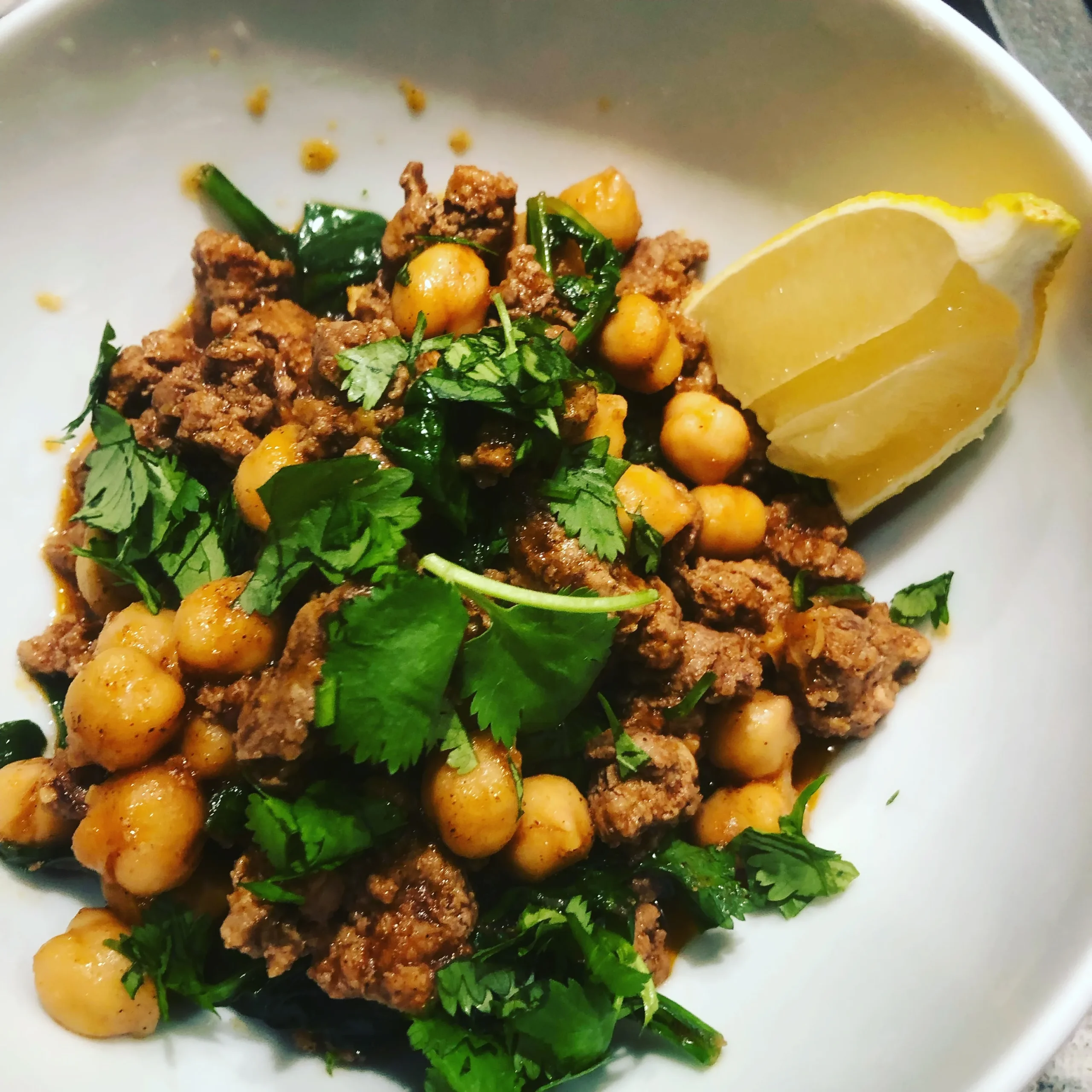 Spiced lamb and spinach stew with chickpeas served in a rustic bowl