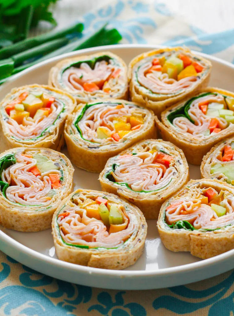 Sliced turkey and cream cheese roll-ups arranged on a white plate